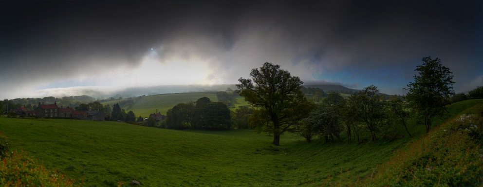 Panoramic view of a lush green landscape under a cloudy sky.