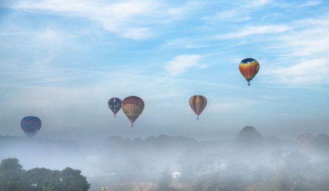 Hot air balloons rising from the early morning mist