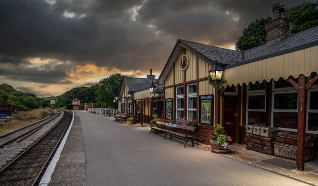 Bolton Abbey Heritage Railway at dusk. Historic train station with platform, benches, and cloudy sky at sunset.
